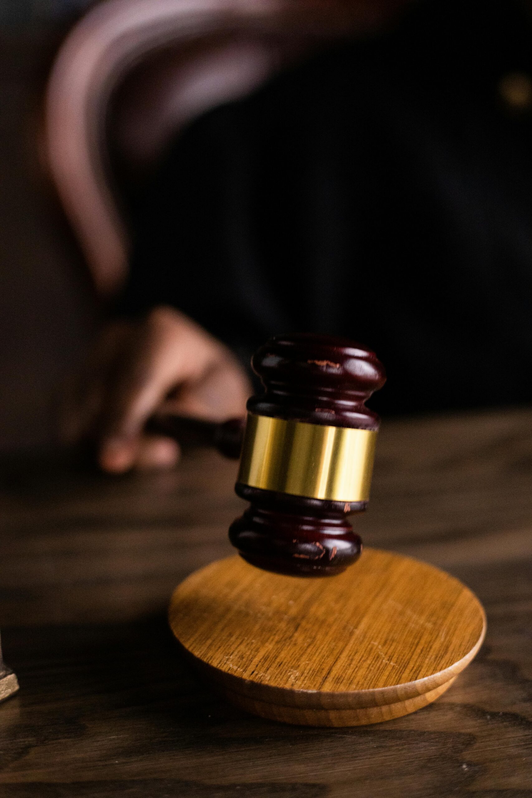 Wooden gavel with brass band on dark surface